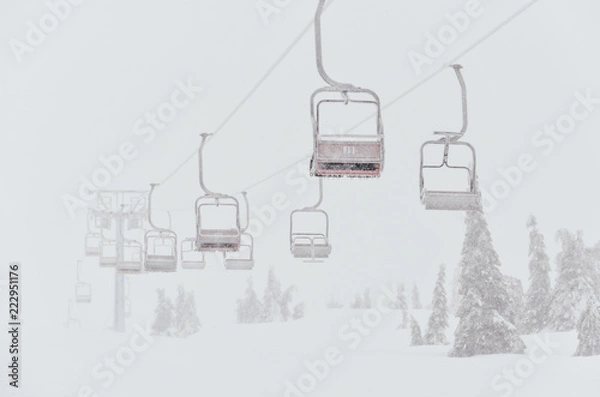 Fototapeta Chairs of a ski lift heading into the fog