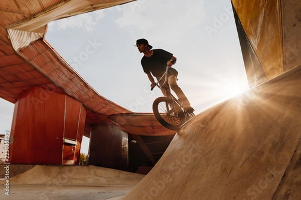 Fototapeta BMX rider makes a TAilwhip trick. Young man doing tricks in the air on a BMX bike. BMX freestyle