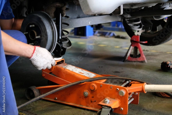 Fototapeta mechanic replace shock absorber & spring in auto repair garage
