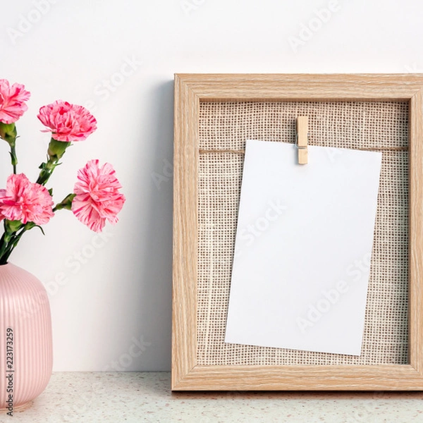 Fototapeta A square photo of terrazzo desk with wooden frame mockup and pink carnations in a notched vase