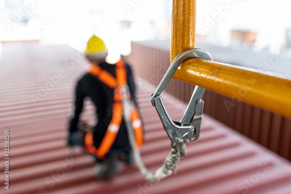 Fototapeta Construction worker wearing safety harness and safety line working at high place.