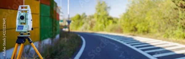 Fototapeta Panoramic view of surveyor equipment (theodolite or total positioning station) on the construction site of the motorway or road