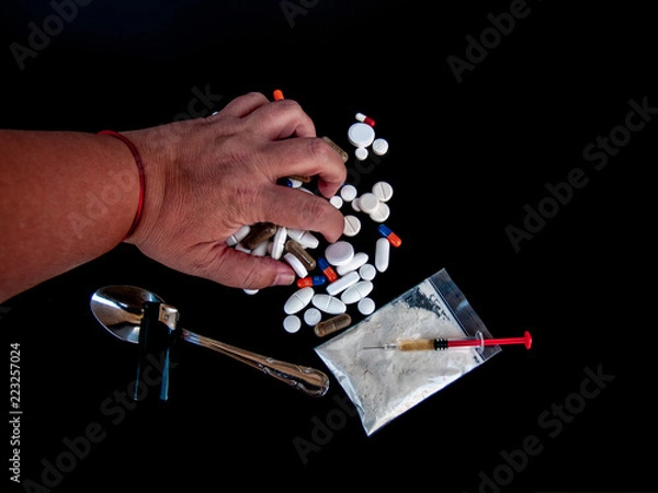 Fototapeta One person catchting with their hand pills of different sizes, shapes and colors, drugs and syringes Concept of drugs and alcohol