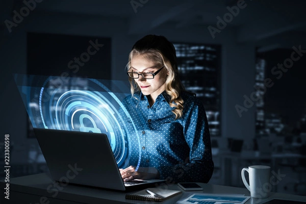 Obraz Beautiful blonde in dark office working on laptop and getting ne