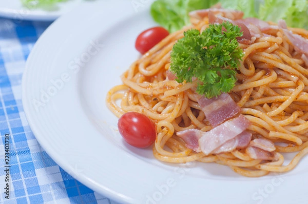 Fototapeta close up of delicious spaghetti with bacon and tomatoes on white plate and , Select focus
