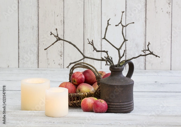 Fototapeta Rustic decoraton with apples, candles and twigs in a vase on a white wooden background, perfect for scandi-chic style winter and autumn mood