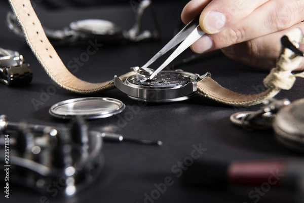 Fototapeta Detail of the work of a watchmaker who replaces a battery / Close up of replacing a watch battery with watchmaker tools