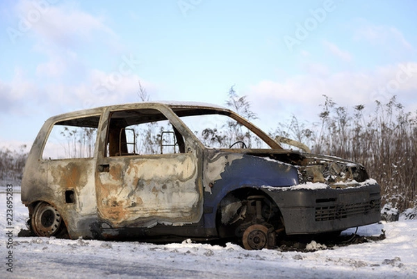 Fototapeta Spalone auto stojące przy drodze zimą.