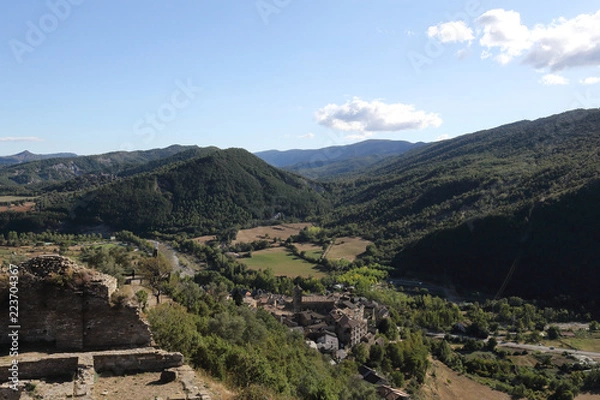 Fototapeta A landscape of cultivated fields, dense forest and mountains as seen from the ruins of the abandoned castle in the rural medieval town of Boltaña, in the Spanish Aragonese Pyrenees