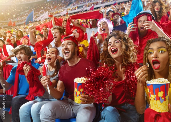 Obraz Young sport supporter happy fans cheering at stadium. Group of young woman and man support the football team during the match