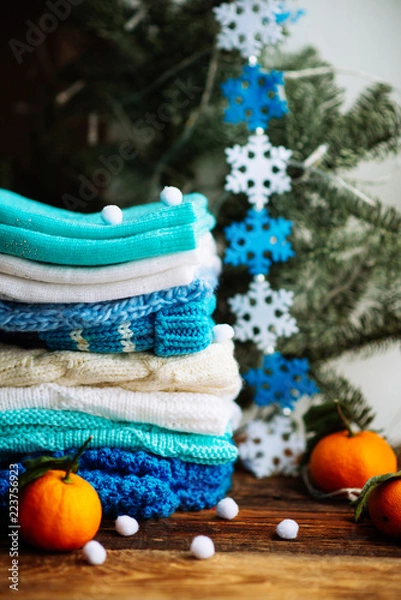 Fototapeta Knitted things. Sweaters are lying on a wooden table. Candles. Autumn. Cozy.