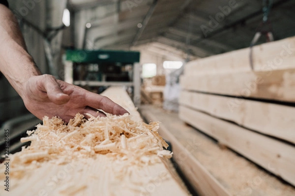 Obraz hand sweeps sawdust from a wooden beam