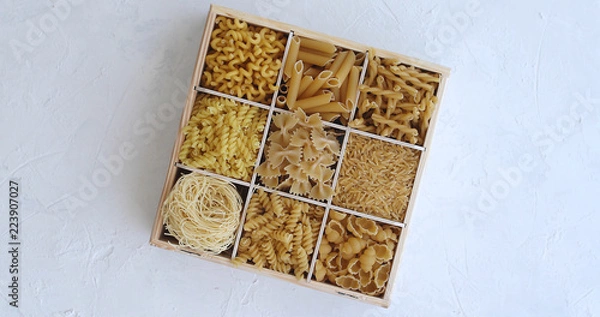 Fototapeta From above view of white box divided into sections with macaroni of different shape on white background