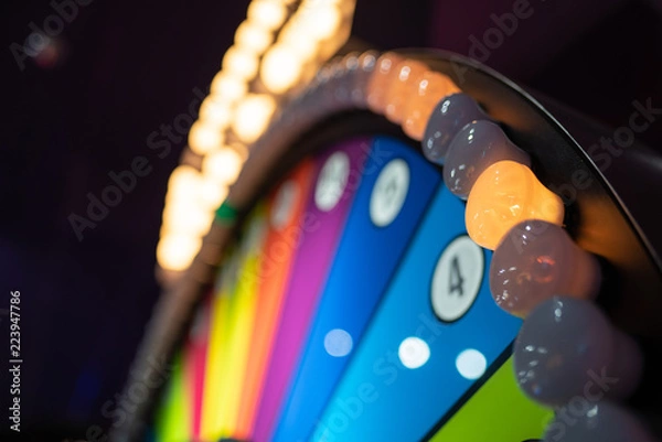 Fototapeta Arcade gambling machine up close. Giant wheel with colorful sections and lights.