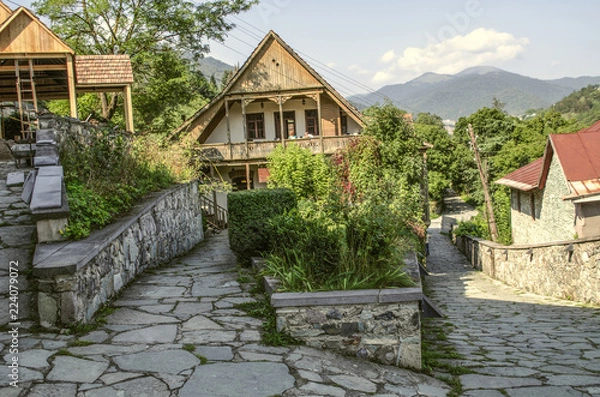 Obraz Widok przecinających się brukowanych uliczek ze starymi kamiennymi domami z drewnianymi balkonami i kratami z kutego żelaza w Muzeum Tufenkian Old Dilijan