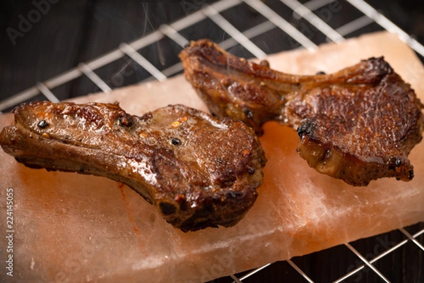 Obraz Tow lamb chops cooking at himalayan rock salt block