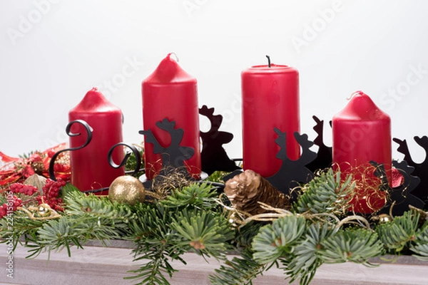 Fototapeta Four traditional red advent candles with christmas decoration. Isolated on white background