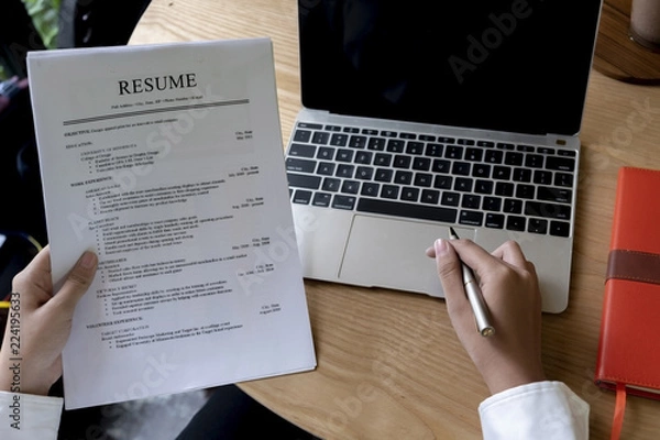 Fototapeta Business man review his resume application on desk, laptop computer, job seeker