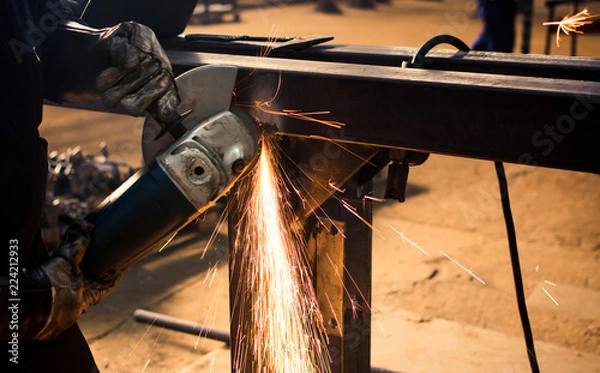 Fototapeta Worker grinding metal with angle grinder