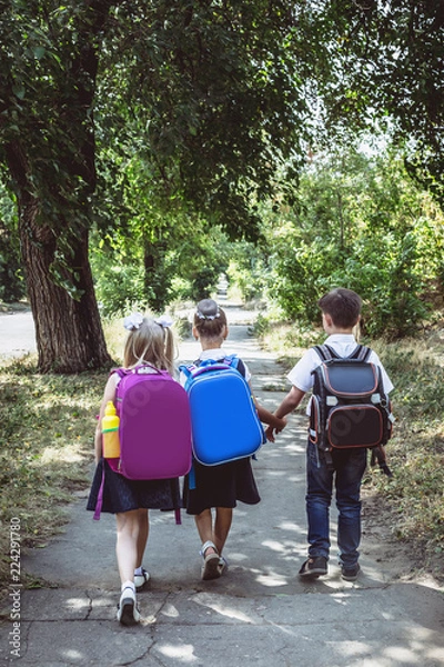 Fototapeta Three elementary school students with backpacks