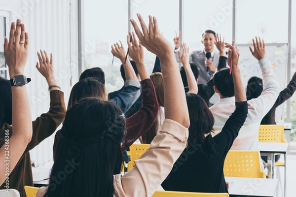 Fototapeta Audience raising hands up while businessman is speaking in training at the office.