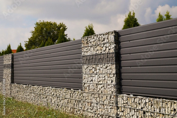 Fototapeta Wall. House fence with an interesting use of gabions and steel panels.