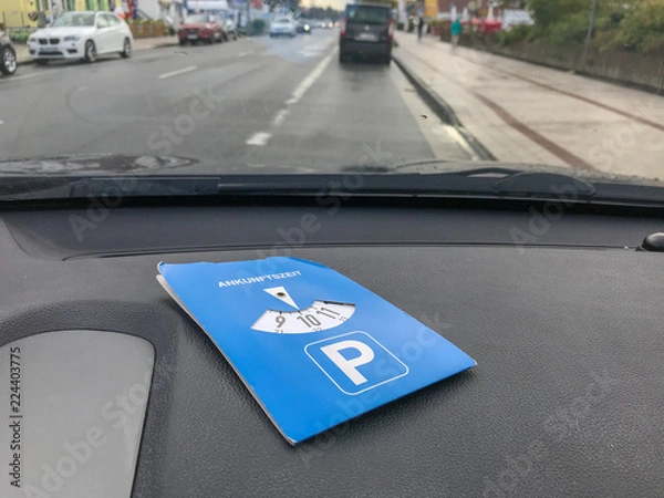 Fototapeta Blue parking disk lying in the dashboard of a car