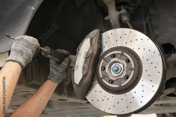 Fototapeta  Mechanic repairing a car with replace brake disc and pads