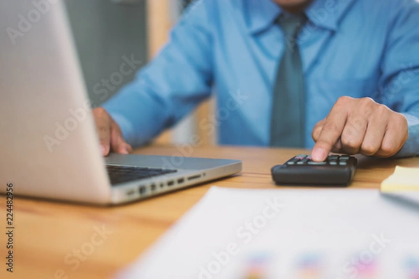 Fototapeta calculate,finance,accounting,Business people analyzing investment charts with calculator .Accounting technology,using laptop at office,Analyze plans document paper graph chart business marketing plan.