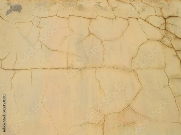 Fototapeta Plastered and painted yellow wall, covered with numerous cracks, texture for background