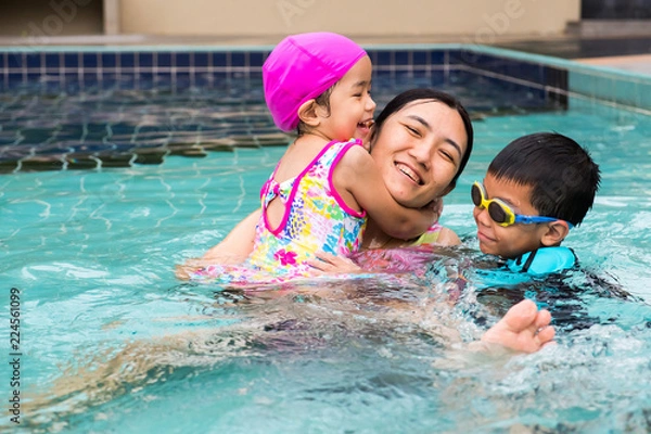 Fototapeta family spent time to swim in swimming pool. they enjoy playing together with laughing