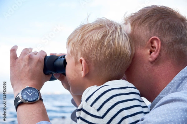 Obraz Close up portrait of boy and man sit at the deck and looks through binoculars