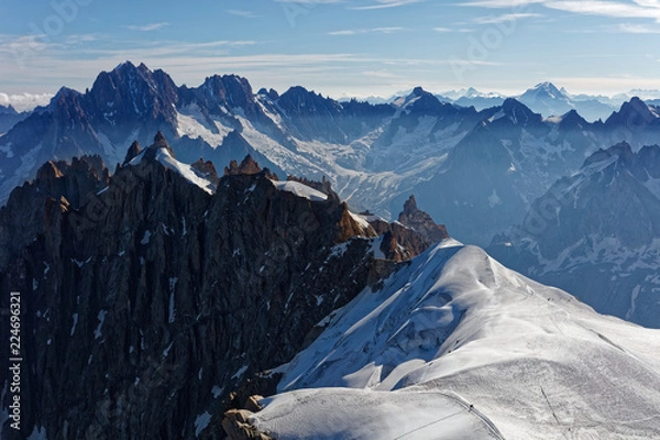 Fototapeta Chamonix, south-east France, Auvergne-Rhône-Alpes. Climbers heading for Mont Blanc. Descending from Aiguille du Midi cable car station towards sunny snow planes and glaciers on border of France
