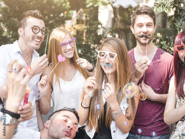 Obraz group of friends doing a photo boot with props outdoor