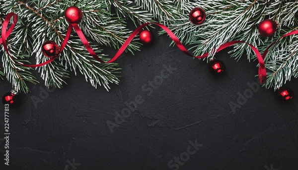Fototapeta Horizontal black stone background with fir branches decorated with red balls. Top view. Space for text