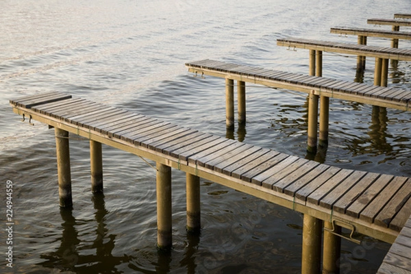 Fototapeta Yachts and boat berths with empty spaces. Coastal landscape in background.