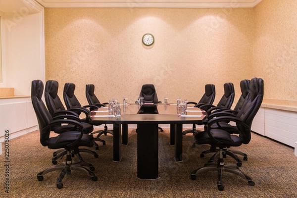 Fototapeta Conference room for business meetings large table in the middle of the room around comfortable chairs on the wall hang the clock
