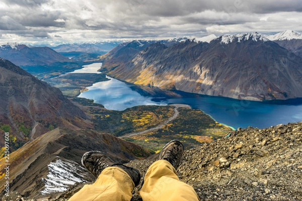 Fototapeta Adventure concept, resting male legs in front of the stunning landscape. Yukon, Canada