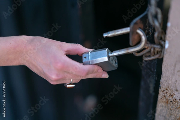 Fototapeta Close up of hand on padlock and chain