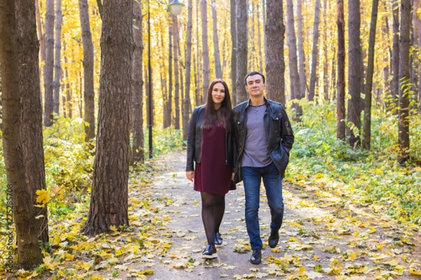 Fototapeta Couple in love holding hands and walking through a park on a sunny autumn day