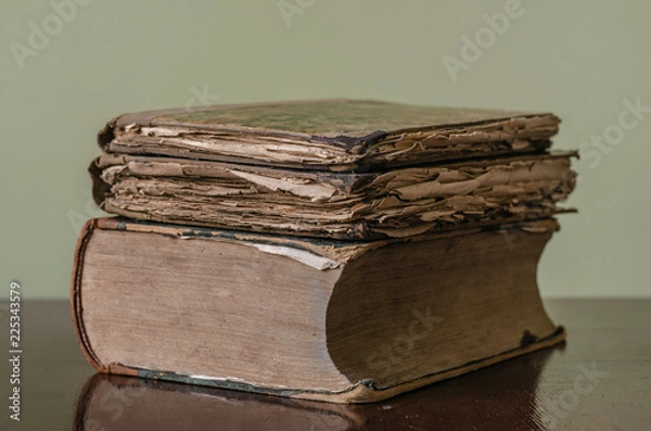 Fototapeta Ancient medieval worn books with yellow sheets stacked on a table