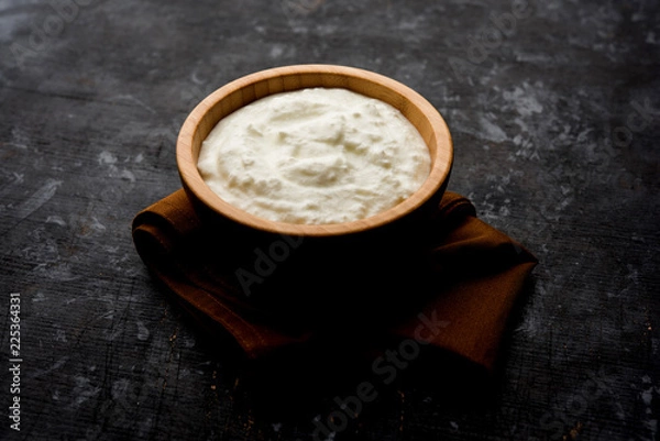 Fototapeta Plain curd or yogurt or Dahi in Hindi, served in a bowl over moody background. Selective focus