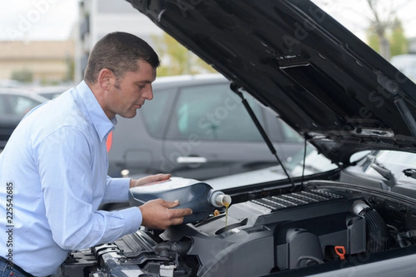Fototapeta mechanic changing motor oil to engine