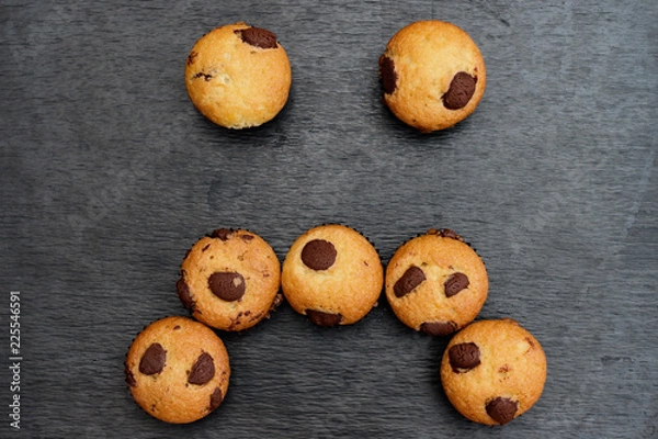 Fototapeta Chocolate chip muffins with sad face shape.