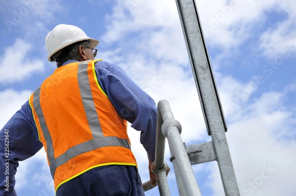 Obraz Construction foreman and worker overlooks site wearing hard hat and high visability vest and clothing for safety.
