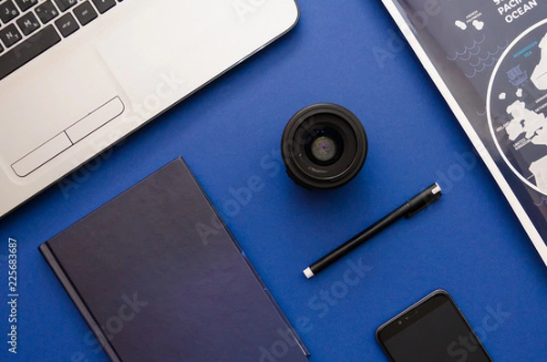 Fototapeta Photographer's equipment such as laptop, lense and notebook on the blue background