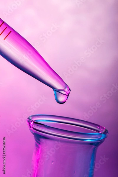Fototapeta Close up on a drop on tip of pipette in pink light