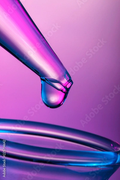 Fototapeta Close up on a drop on tip of pipette in pink light