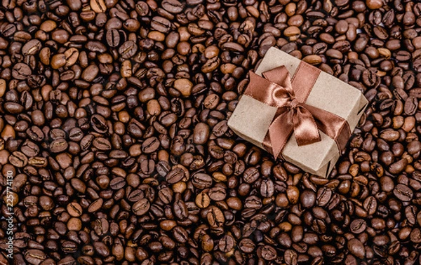 Fototapeta Gift box with ribbon on coffee background.  Roasted coffee beans background. Copy space