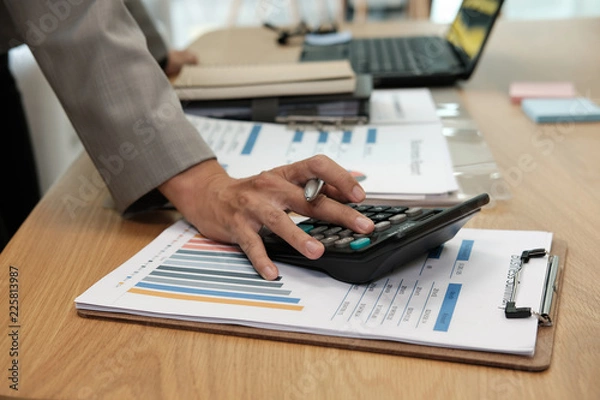 Fototapeta financial adviser use calculator to calculate revenue & budget. accountant doing accounting. bookkeeper making calculation. finance & economy concept